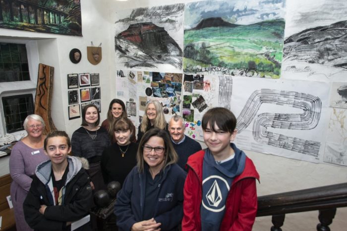 9 people of a wide range of ages standing with nature themed artwork